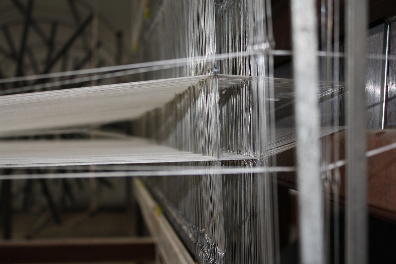 Close-up of a loom with threads and wooden beams in a workshop setting